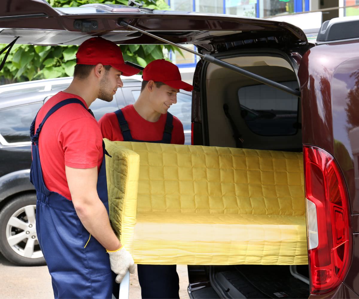 Günstig umziehen in Ratingen: Umzugshelfer laden ein gelbes Sofa in einen Transporter