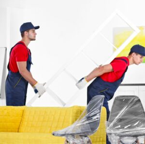 Umzug in Ratingen Zwei Helfer tragen ein Möbelstück an einem gelben Sofa vorbei – Umzug in Ratingen
