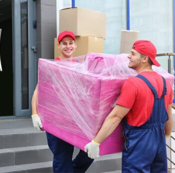 Umzug in Ratingen Zwei Umzugshelfer tragen ein in Folie gepacktes Möbelstück – Umzug in Ratingen