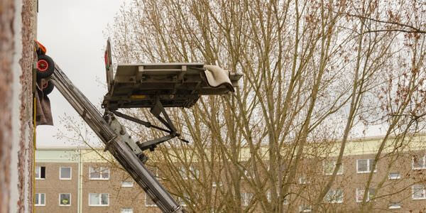 Möbellift zwischen kahlen Bäumen vor einem Gebäude – Möbellift in Ratingen