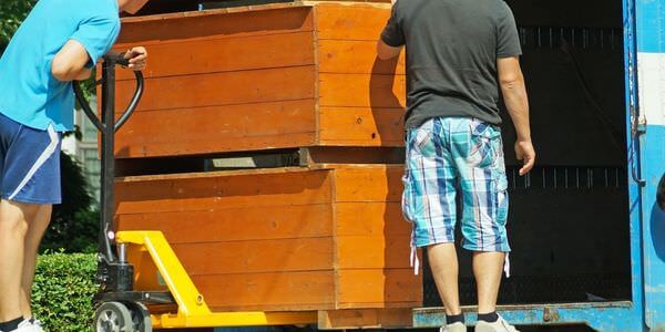 Möbellift Ratingen: Zwei Helfer tragen einen Holzschrank aus einem Lkw